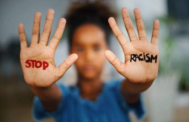 Person holding their hands in front with word 'Stop' on right hand and 'Racism' left hand