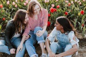 Three women laughing and being happy with flowers in the background.