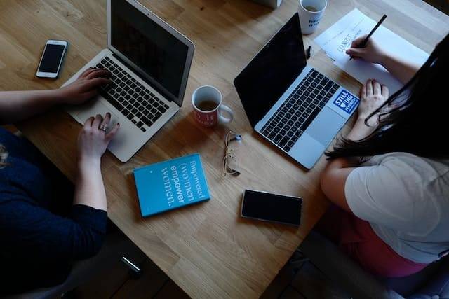 Two women working on laptops at an office.