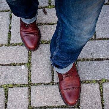 Person wearing brown shoes taking a step forward with their left foot.